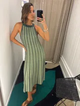 Vestido largo de tejido de punto verde con rayas verticales negras, sin mangas y cuello halter.