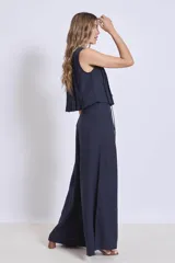 Blusa sin mangas color azul marino, con cuello redondo y detalle de tablas verticales en el frente. Corte corto con terminación fruncida y lazos ajustables en el escote.