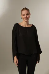 Blusa negra holgada de poliéster con mangas largas y cuello redondo.