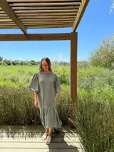 Vestido largo color beige, de corte amplio, con mangas cortas abullonadas y volado en el ruedo.