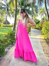 Vestido largo fucsia con tirantes y volantes en la parte inferior.