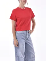 Remera roja de manga corta, corte cropped y cuello redondo con ribete a rayas blancas y doradas.