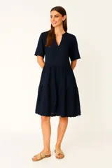 Vestido corto azul marino de algodón con cuello mao, mangas cortas y falda escalonada con detalle de puntilla en ruedo y mangas.