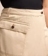 Short pollera de sarga color beige, con parte delantera cruzada, bolsillo con solapa delantero, bolsillos traseros y cintura con ajuste elástico interior.