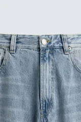 Pantalón de jeans de algodón, corte baggy fit, tiro medio, con efecto lavado en tonos grises y verdes. Presenta cinco bolsillos y cierre frontal con cremallera y botón.