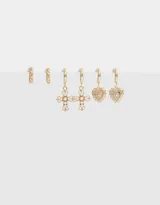 Set de aros dorados que incluye dos argollas pequeñas con diseño torzado, dos argollas con dije de cruz con perlas y dos argollas con dije de corazón con diseño floral.