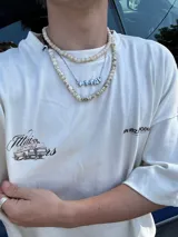 Remera amarilla con estampado en la espalda de una camioneta con una chica y una tabla de surf.