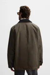 Parka relaxed fit color verde oscuro confeccionada en tejido de algodón con acabado encerado. Tiene cuello solapa combinado en pana negra, manga larga acabada en puño ajustable con botón a presión, bolsillos frontales de plastrón con solapa, bolsillo interior y cierre frontal de botonadura oculta por solapa.