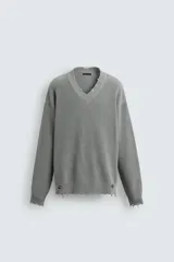 Sweater gris de punto con cuello en V, manga larga y terminaciones irregulares con efecto desgastado.