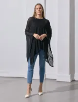 Poncho negro de tejido calado con lurex, terminación asimétrica y cuello redondo.