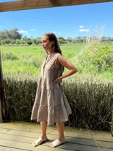 Vestido verde militar de lino, corte a la rodilla, sin mangas, con cuello mao y botones de nácar. Presenta varios cortes en su largo, aportando movimiento y un toque moderno a este diseño fresco y elegante.