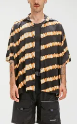 Camisa de manga corta con estampado de rayas horizontales difuminadas en tonos beige y negro, de calce oversize y canesú en la espalda.