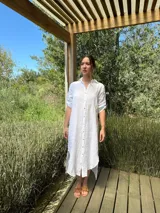 Vestido camisero largo de lino blanco, con corte en la cintura, abertura lateral y botones de nácar.