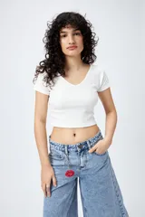 Top blanco de algodón con mezcla de poliéster y elastano, con escote en V delantero y trasero.