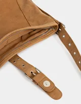 Cartera hobo color marrón claro de cuerina con correa regulable y hebilla decorativa frontal.