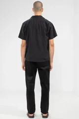 Camisa negra de manga corta con cuello camp y calce relajado. Confeccionada en mezcla de algodón y lino con botones de coco con logo y parche característico de Polonio.