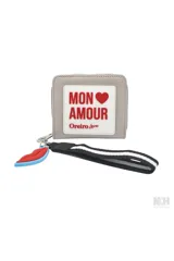Billetera tipo monedero color gris con cierre de cremallera, llavero desmontable con dije de labios y parche frontal con la inscripción "Mon Amour" en rojo.