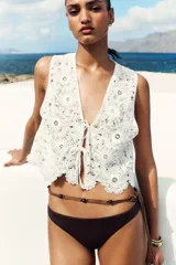 Top chaleco marrón de crochet con escote en pico y cierre frontal con lazos.