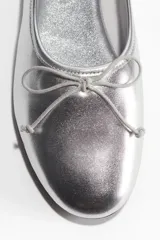 Ballerinas plateadas con punta fina y moño decorativo.