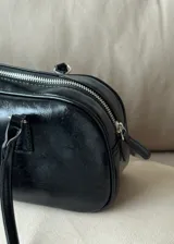 Cartera tipo baguette de cuero sintético color negro con doble asa corta y cierre superior con cremallera.