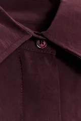 Camisa color borgoña de corte amplio, confeccionada en tejido fluido con modal. Tiene cuello solapa, manga corta con dobladillo y cierre frontal con botones.