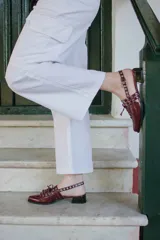 Sueco de cuero negro con cordones, ojales, hebillas y tira trasera regulable con elástico. Tiene taco cuadrado bajo.