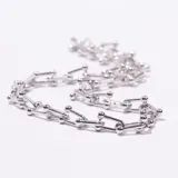 Collar tipo gargantilla plateado con eslabones rectangulares unidos por pequeñas esferas metálicas. Posee un cierre de mosquetón con cadena de ajuste.