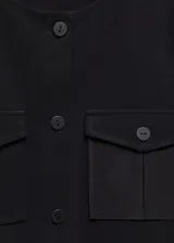 Vestido corto negro de tejido fluido, con cuello redondo y mangas cortas. Presenta trabillas, diseño evasé, dos bolsillos de solapa con botón en el pecho, lazo ajustable y cierre delantero con botones.