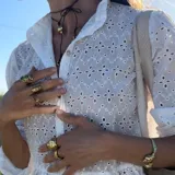 Brazalete rígido dorado con forma de caracola en los extremos.