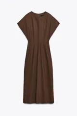 Vestido midi color marrón confeccionado en hilatura con mezcla de algodón y lino. Tiene cuello redondo, manga corta caída y detalle de pliegues en la cintura. Cierre en la espalda con abertura y botón.