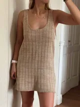 Vestido corto de tejido de punto color beige/dorado, con escote redondo y tirantes anchos. Presenta un tejido acanalado verticalmente con hilos de lurex que le dan brillo.