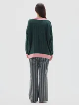 Buzo tejido oversized color celeste, con cuello en V y ribetes negros y blancos. Presenta mangas largas con diseño de trenzas y puños y dobladillo acanalados en color negro.