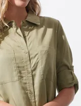 Camisa blanca de lyocell, marca Cyrus. Tiene cuello con solapa, abertura central con botones, mangas largas regulables con presilla y botón, y dos bolsillos delanteros aplicados.