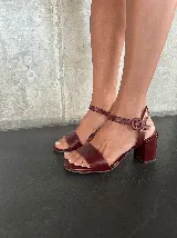 Sandalias de cuero color borgoña, con tira ancha sobre los dedos, pulsera al tobillo con hebilla y tacón bloque.