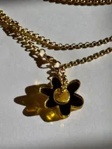 Collar dorado con cadena de eslabones y dije de flor negra con centro dorado.