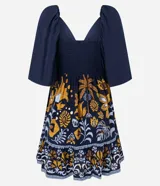 Vestido corto de viscosa con estampado floral y de follaje en tonos mostaza, blanco y azul marino. Presenta escote pronunciado en V con lazo y fruncido en el busto, mangas cortas abullonadas y elástico (lastex) en la espalda. La falda es evasé con un ruedo con volado.