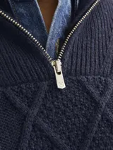 Sweater de punto con cuello alto y cierre metálico a la mitad del pecho. Tejido con diseño de trenzas y rombos.