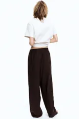 Pantalón marrón de corte holgado en tejido liviano de mezcla de lino. Modelo de tiro alto con cintura elástica y cordón para ajustar fino, bolsillos laterales discretos y piernas rectas.