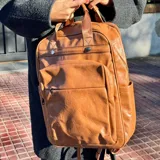 Mochila de cuero color marrón claro con múltiples bolsillos y cierres.