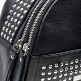 Mochila pequeña negra de cuero con tachas plateadas en el bolsillo frontal. Tiene asa de mano y correas regulables.