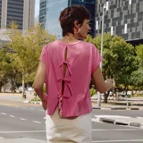 Camiseta rosa de manga corta con espalda abierta y lazos.