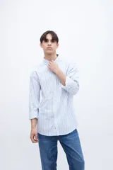 Camisa celeste con rayas verticales blancas, de corte regular, con cuello solapa clásico, bolsillo en el pecho y botones personalizados.