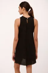 Vestido corto negro de lino italiano, con cuello redondo a la base y musculosa. Tiene detalle de desflecado en el cuello y a lo largo del vestido.