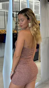 Minivestido strapless color rosa con brillos, corte ajustado y abertura en la cintura.