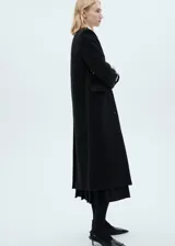 Abrigo negro de corte recto, con cuello de solapa, cierre frontal con botones, bolsillos de ribete y forro interior.