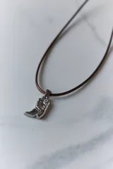 Dije dorado con forma de bota cowboy con detalles calados.