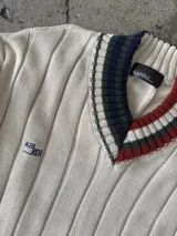 Buzo tejido verde con escote en V, cuello con rayas blancas y azul marino, y puños y ruedo con detalle de rayas.