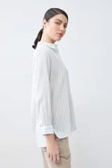 Camisa oversize celeste y blanca a rayas verticales, con cuello mao y mangas largas con puños abotonados.