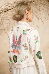 Campera color crema de algodón con estampado de flores, plumas y colibríes, con cuello camisero, cierre frontal con botones metálicos y mangas largas.