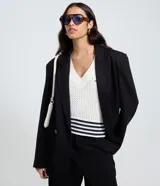 Blazer negro de mujer, modelo largo, con solapas y cierre cruzado de doble botonadura.